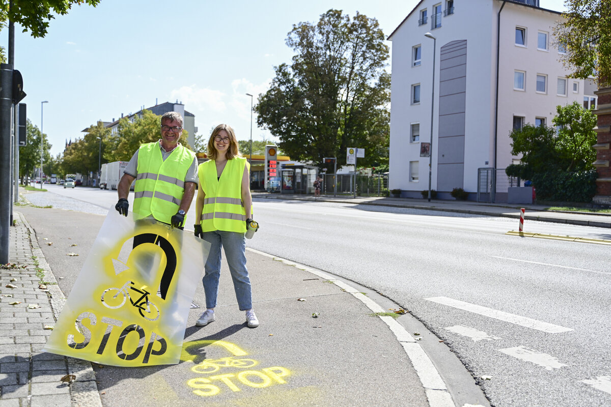 Fahrradbeauftragte Theresa Schneider und Ulrich Sch&auml;pe vom Amt f&uuml;r Verkehrsmanagement und Geoinformation bringen Hinweise auf dem Fahrradweg auf. 